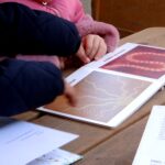In giardino, due bambine osservano un albo illustrato