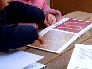 In giardino, due bambine osservano un albo illustrato
