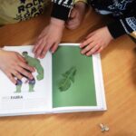 Bambini che provano ad identificare il colore di una foglia usando un libro con un campionario cromatico